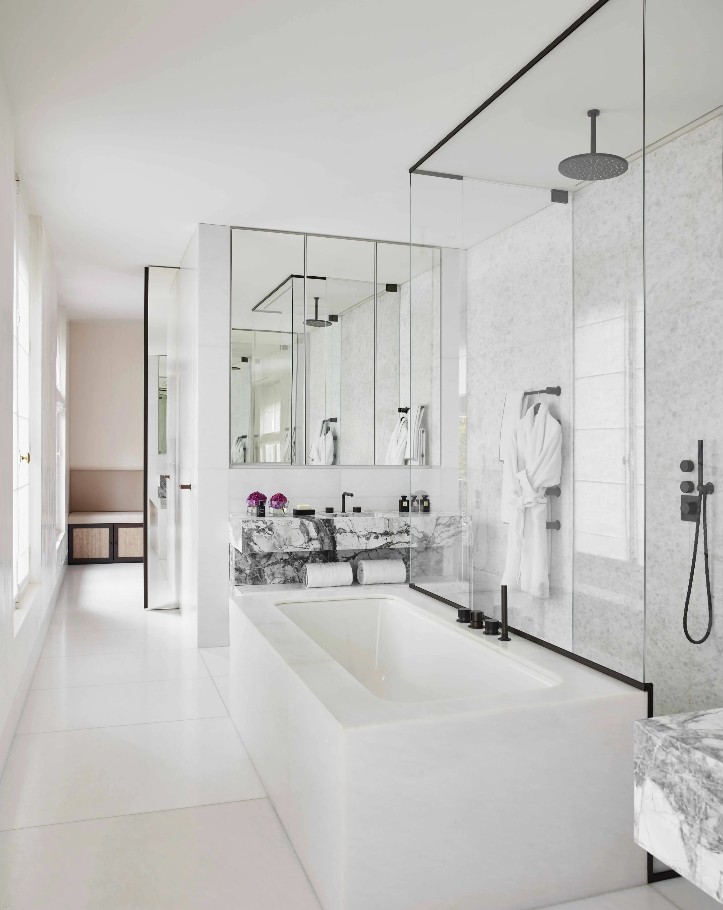 Salle de bain moderne avec baignoire, douche à l'italienne en verre, miroir, towels, et accessoires de salle de bain.