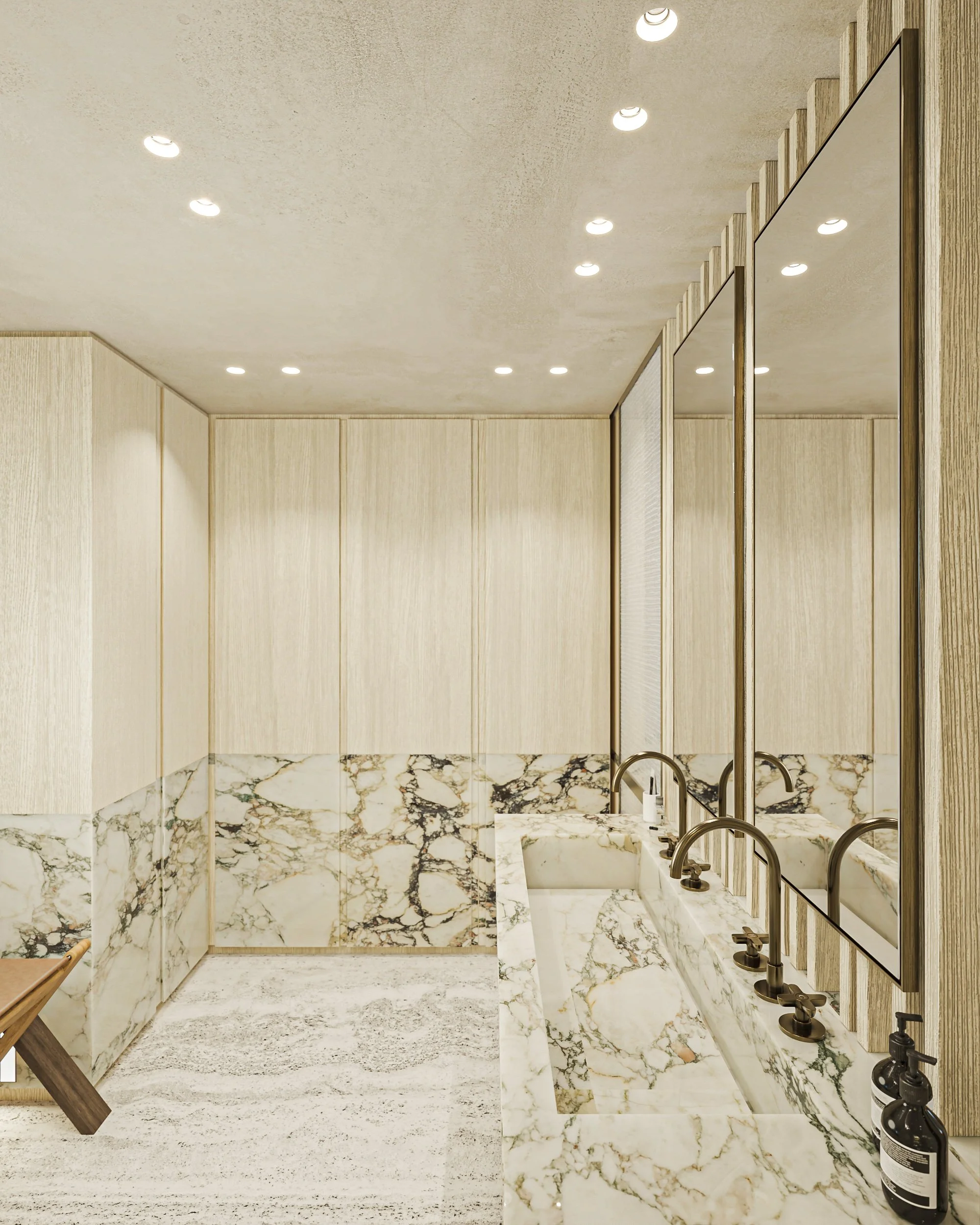 Salle de bain avec murs en bois clair, comptoir en marbre avec deux lavabos, grand miroir, et carrelage en marbre au mur, éclairage encastré au plafond