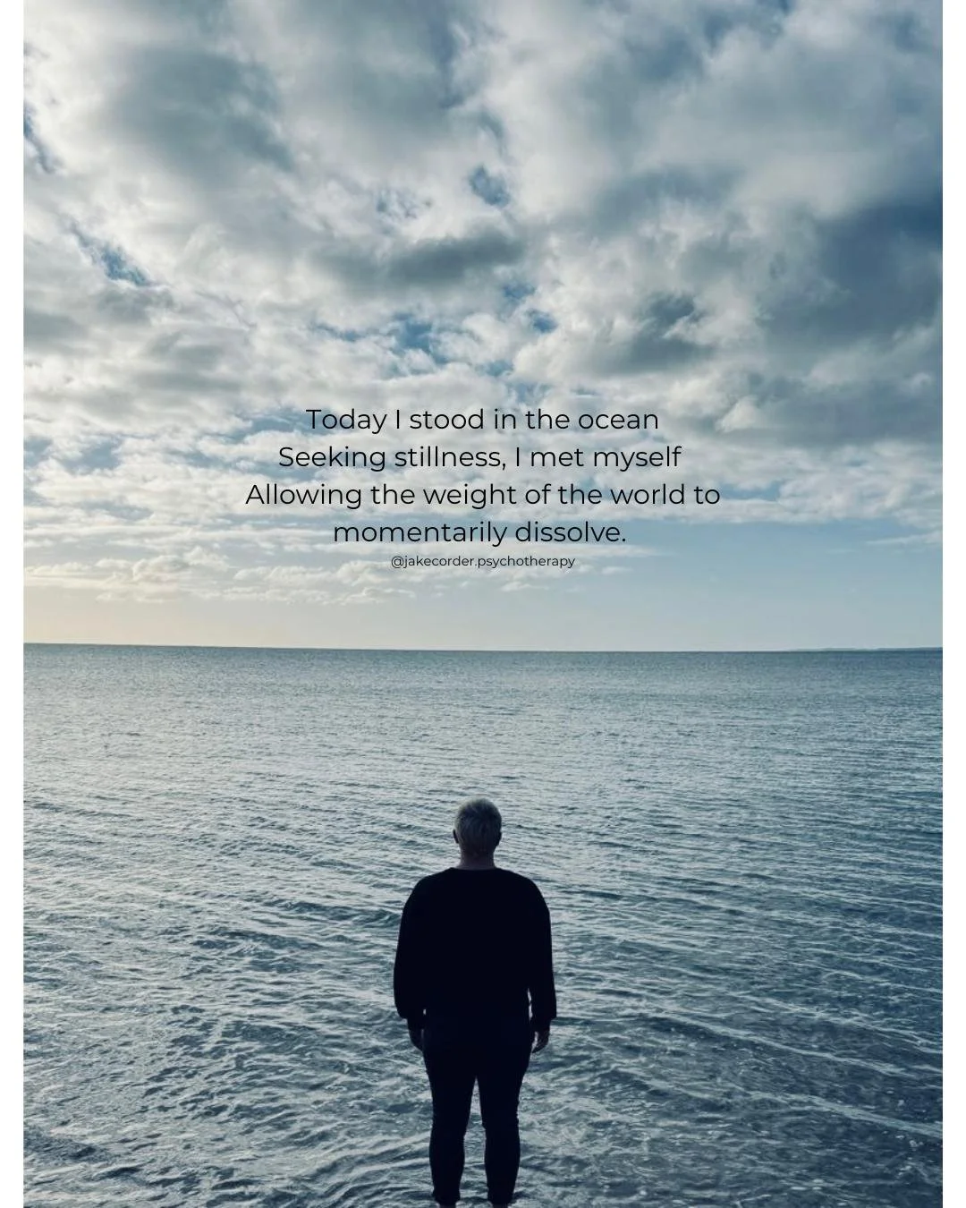 Jake standing at the edge of the ocean, looking at the water with a cloudy sky above.