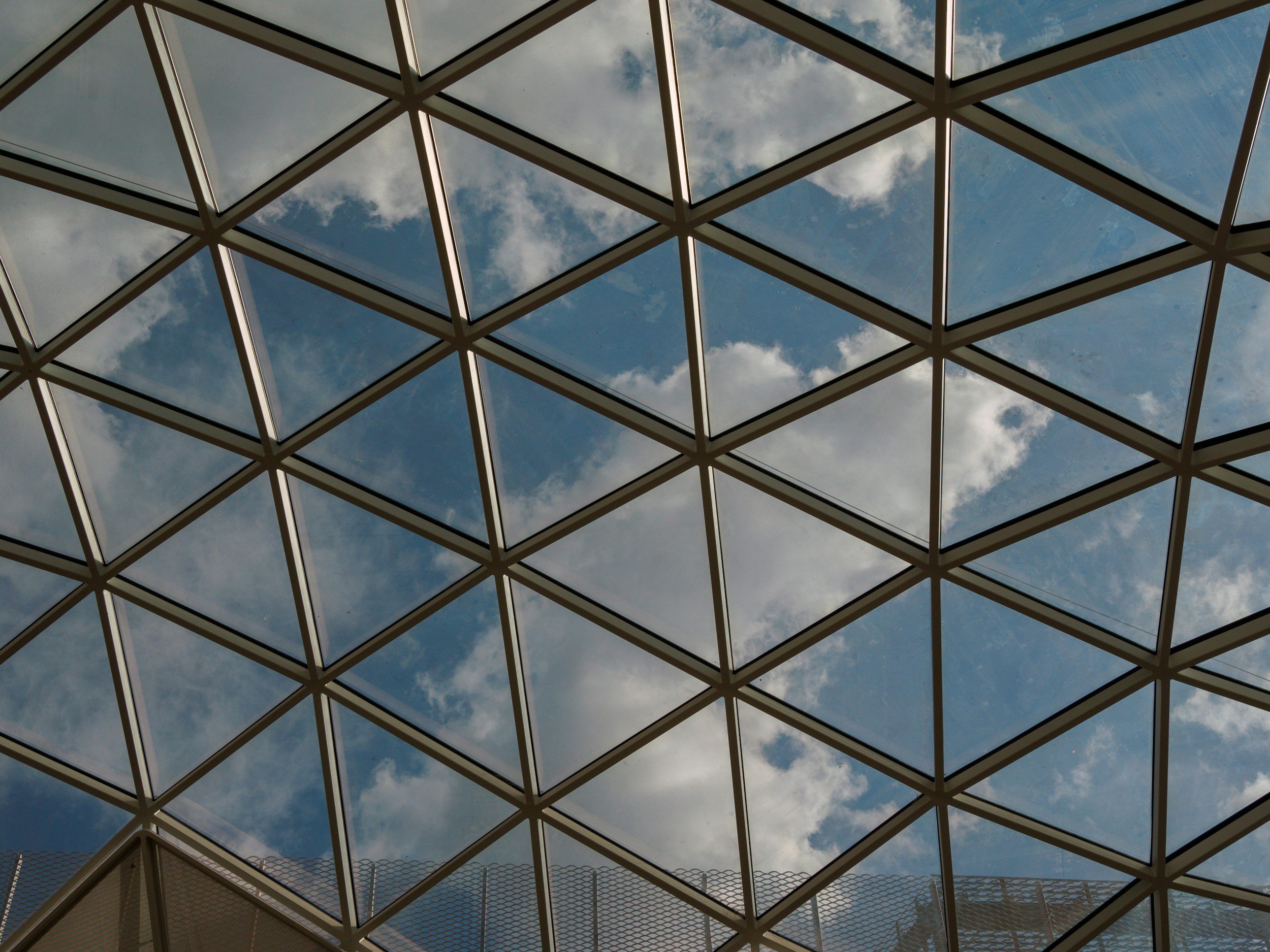Modern geometric glass atrium ceiling, illustrating complex structural architecture and ethical frameworks.