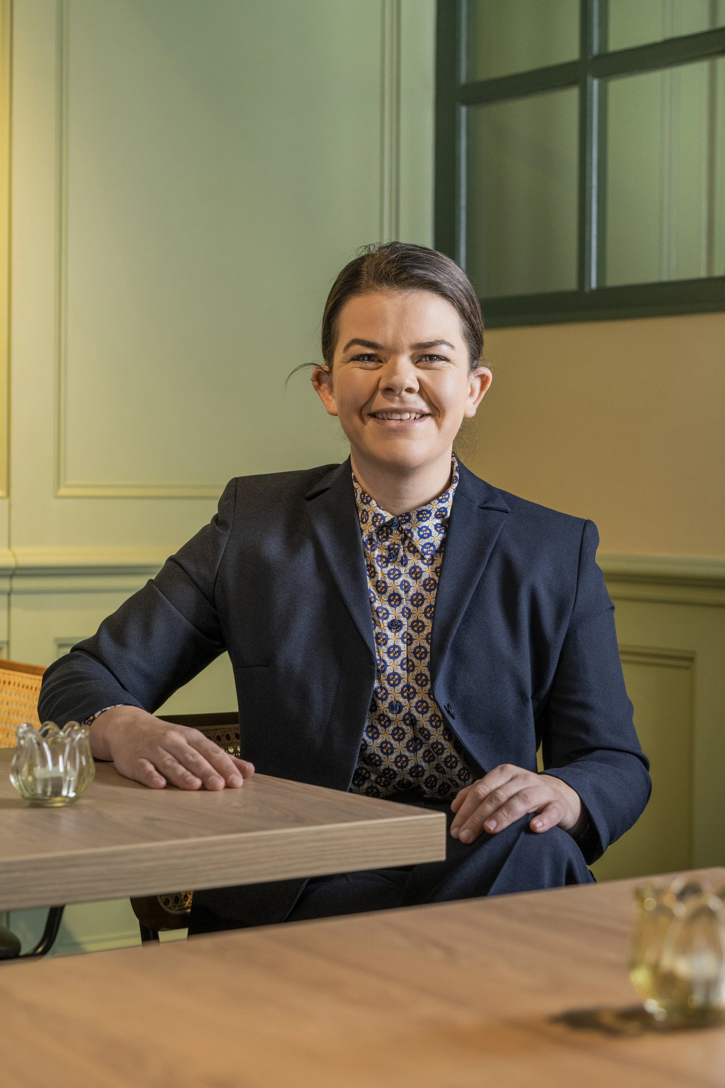 Hannah, Restaurant Manager of the Old Town Bistro, sitting at a table in the main dining room.  There is a small glass pitcher on the table.