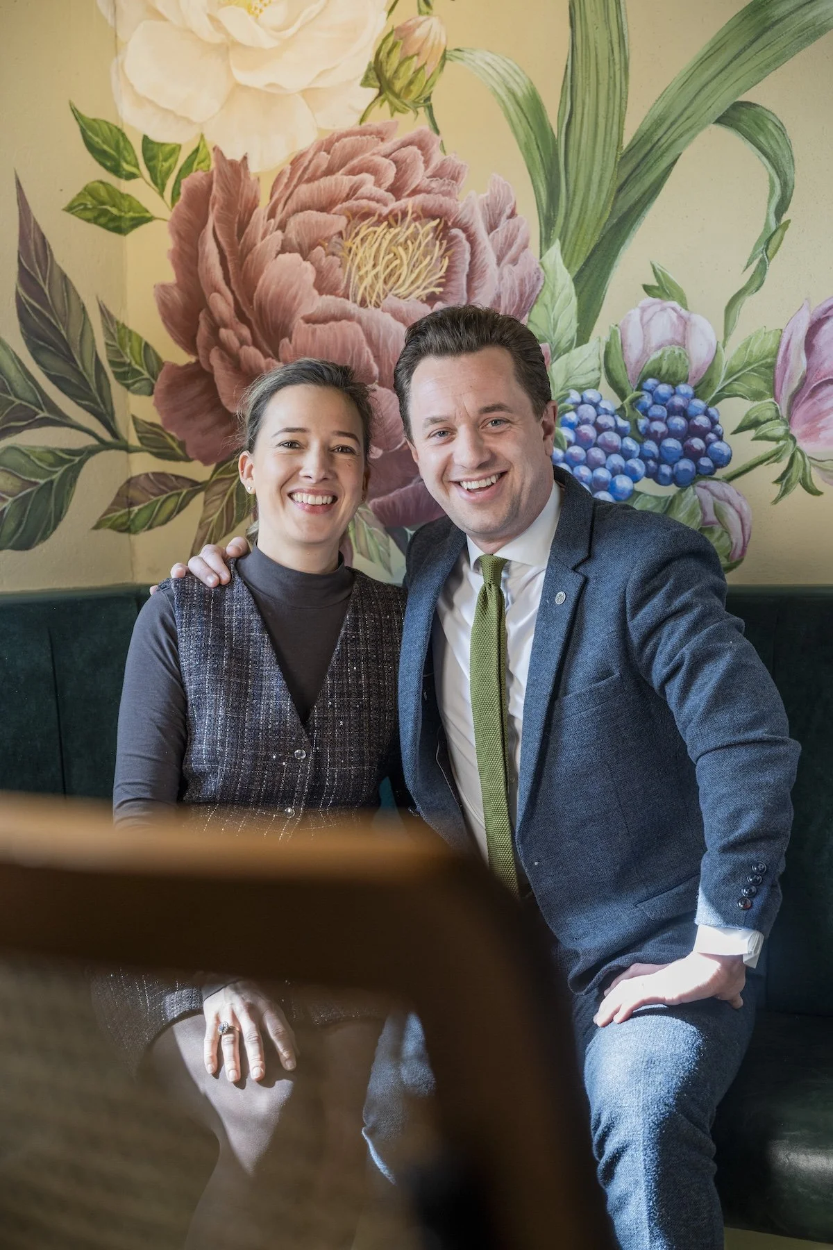 Daniel and Margriet, the owners of Old Town Bistro sitting in front of a floral painted wall.