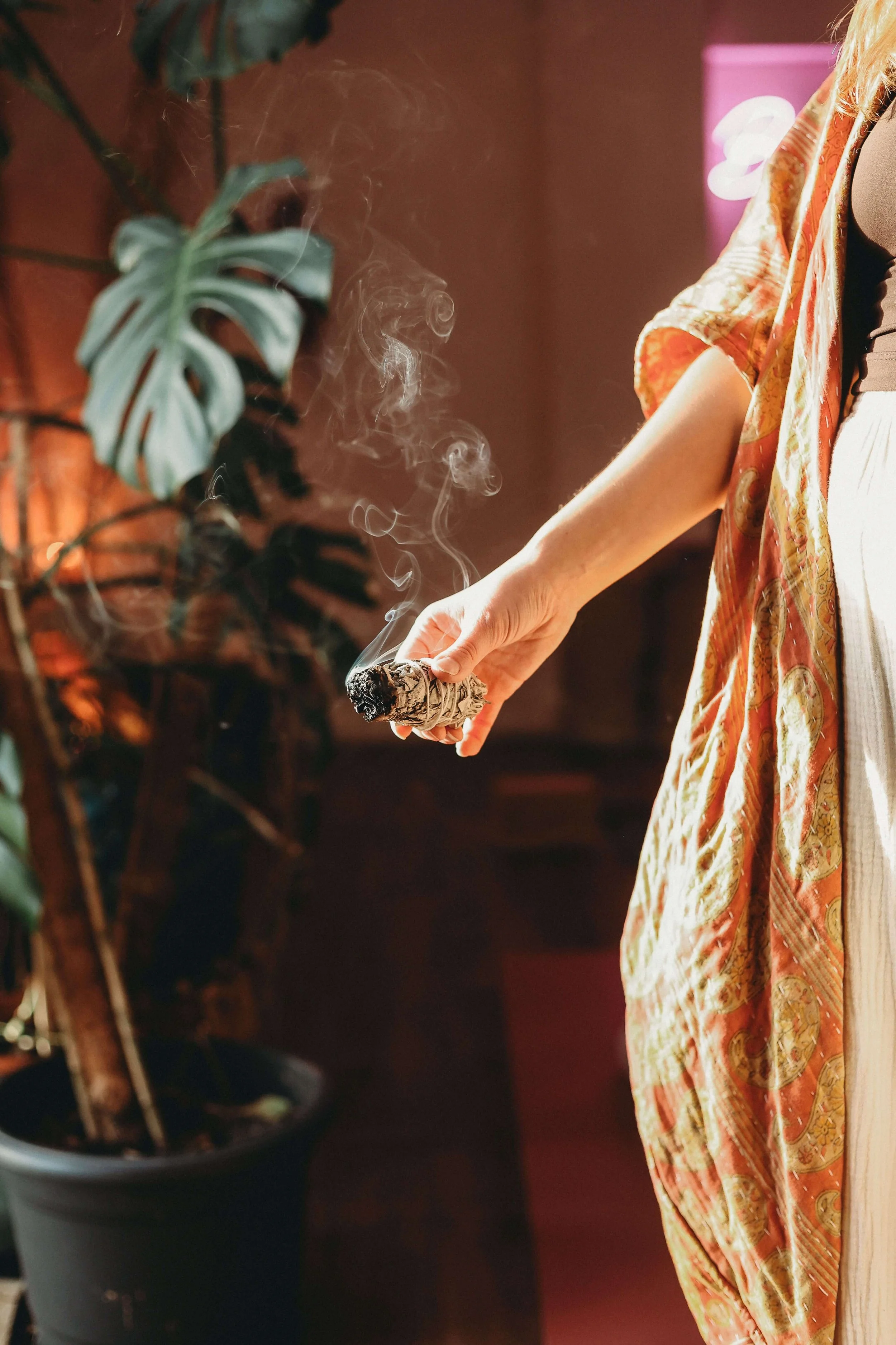 A woman in an orange kaftan burns sage at Yomi, a friendly yoga studio in Market Harborough Leicestershire