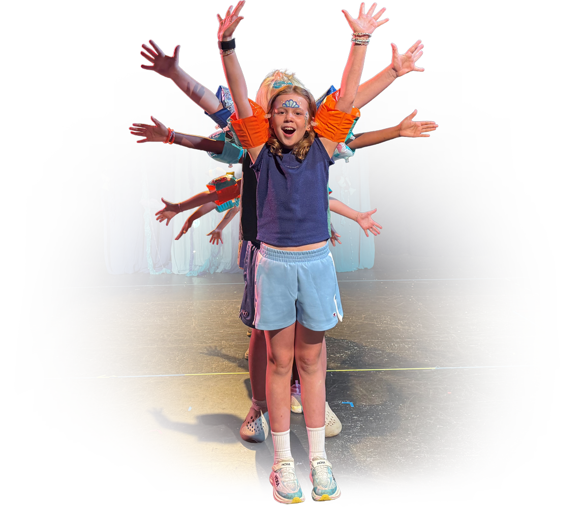 Children performing a dance or act on stage, with the girl in front and others behind her with their arms extended outward.