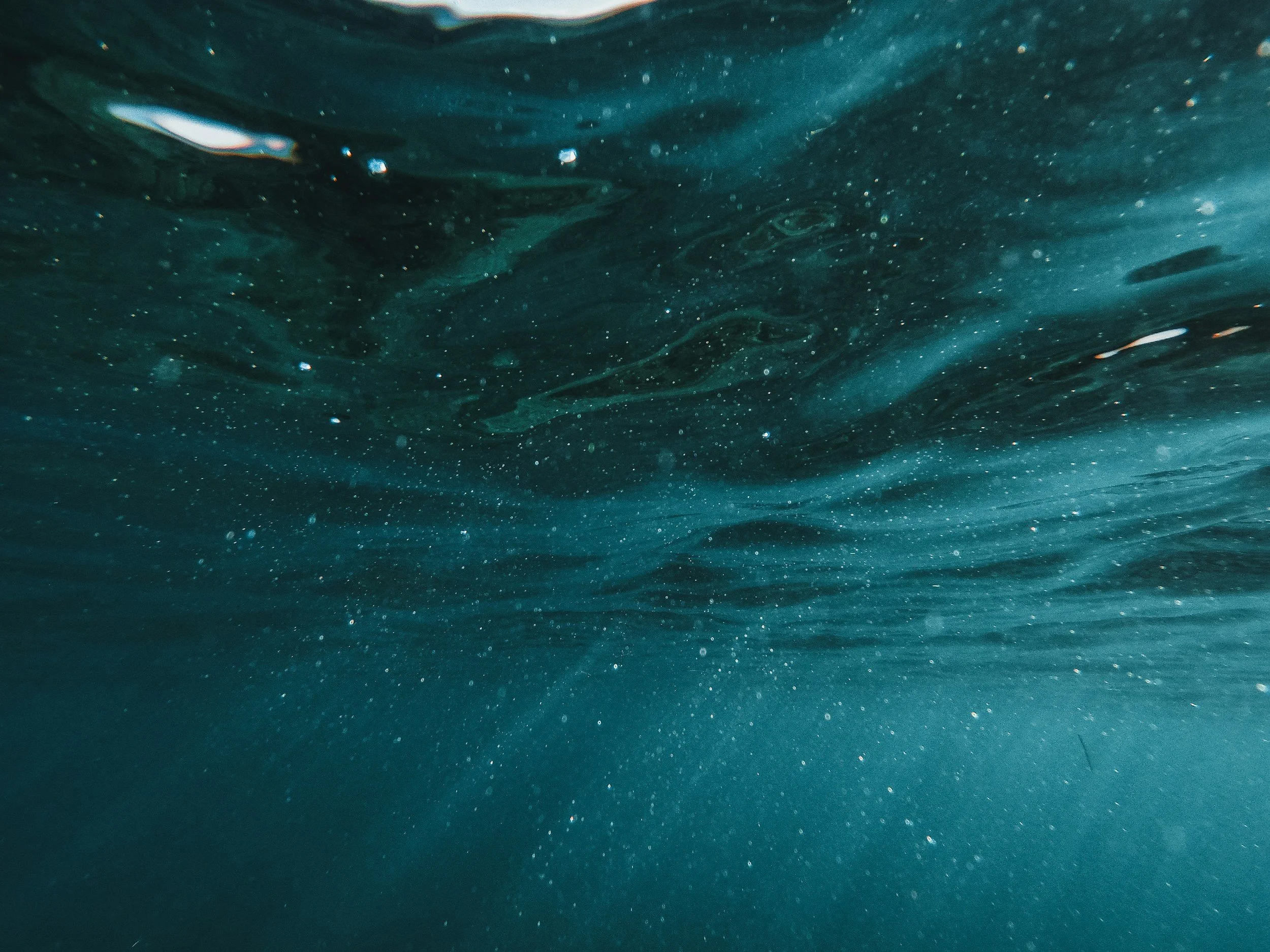 Underwater view showing the surface of the water with bubbles and swirling currents.