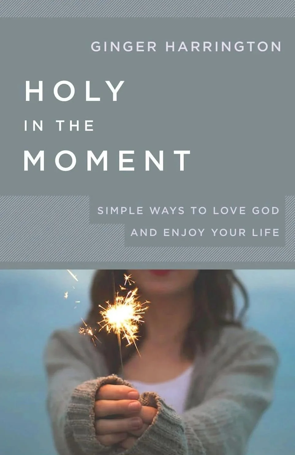 Book cover titled "Holy in the Moment" by Ginger Harrington, featuring a woman holding a lit sparkler with a blurred background.