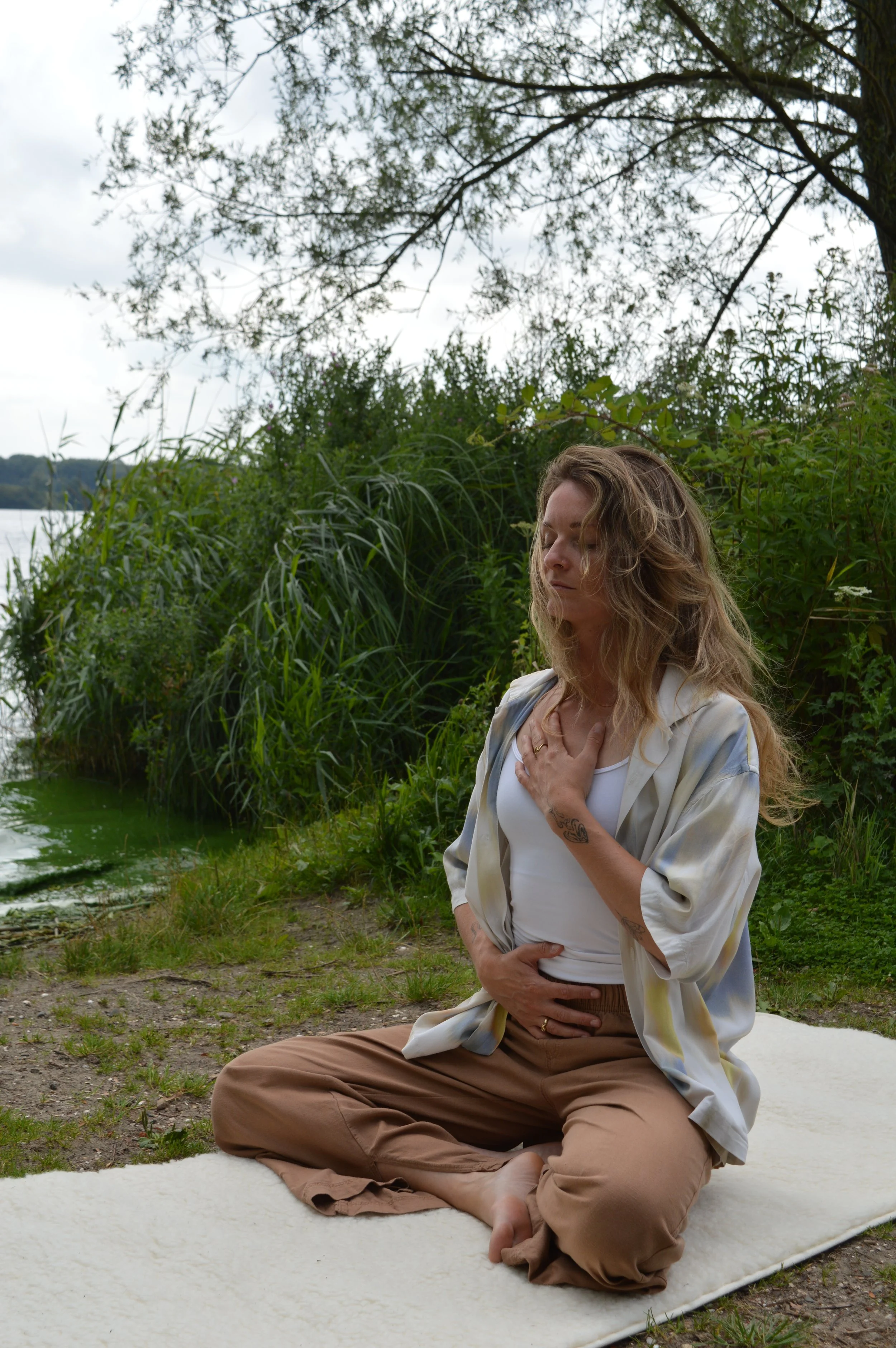 Nadia van Wylde Roots buiten in de natuur, ze doet een ademoefening met haar handen op het hart en de buik.