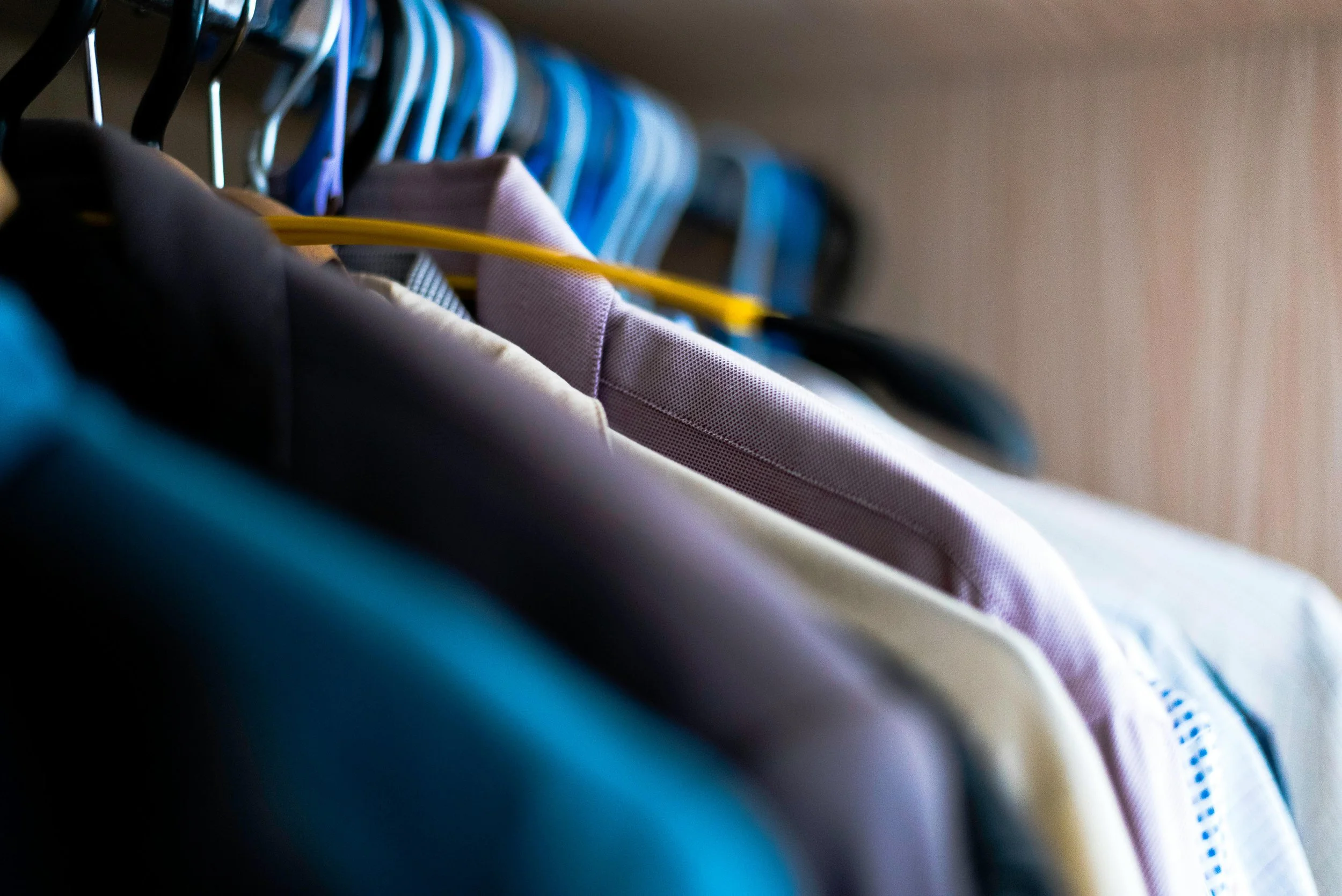 Clothing hanging on a closet rod, including shirts and jackets on hangers.
