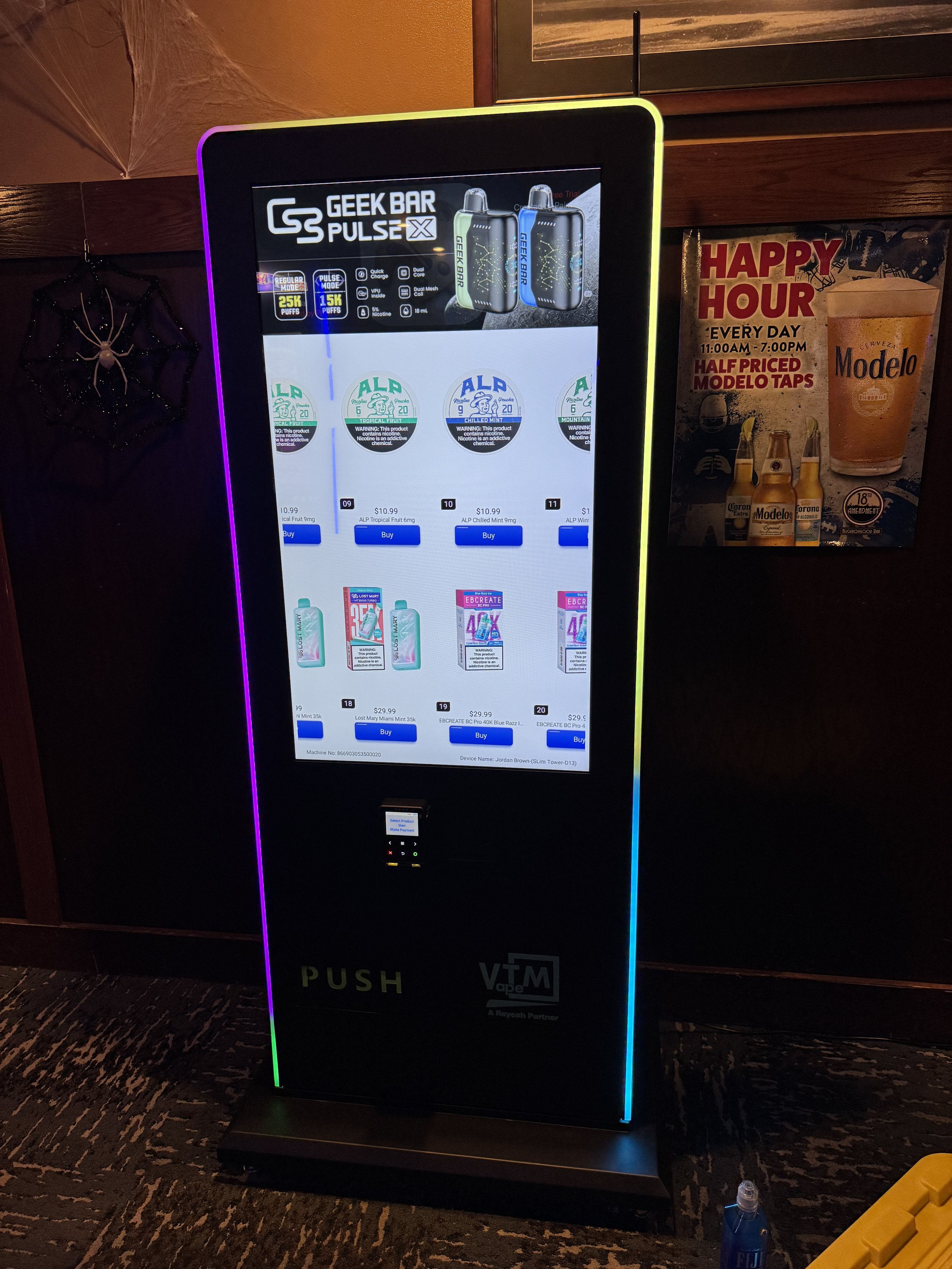 Vape product vending kiosk with a digital display showing various vape products and prices, illuminated with colorful LED lighting.
