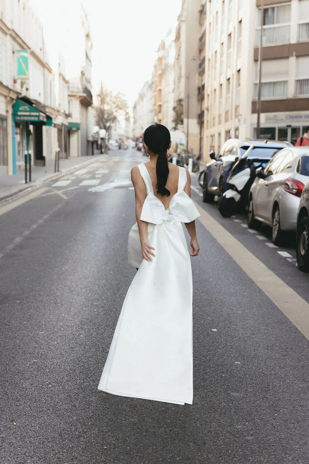 Silhouette de mariée vue de dos, robe fluide et grand nœud pour une allure couture.
