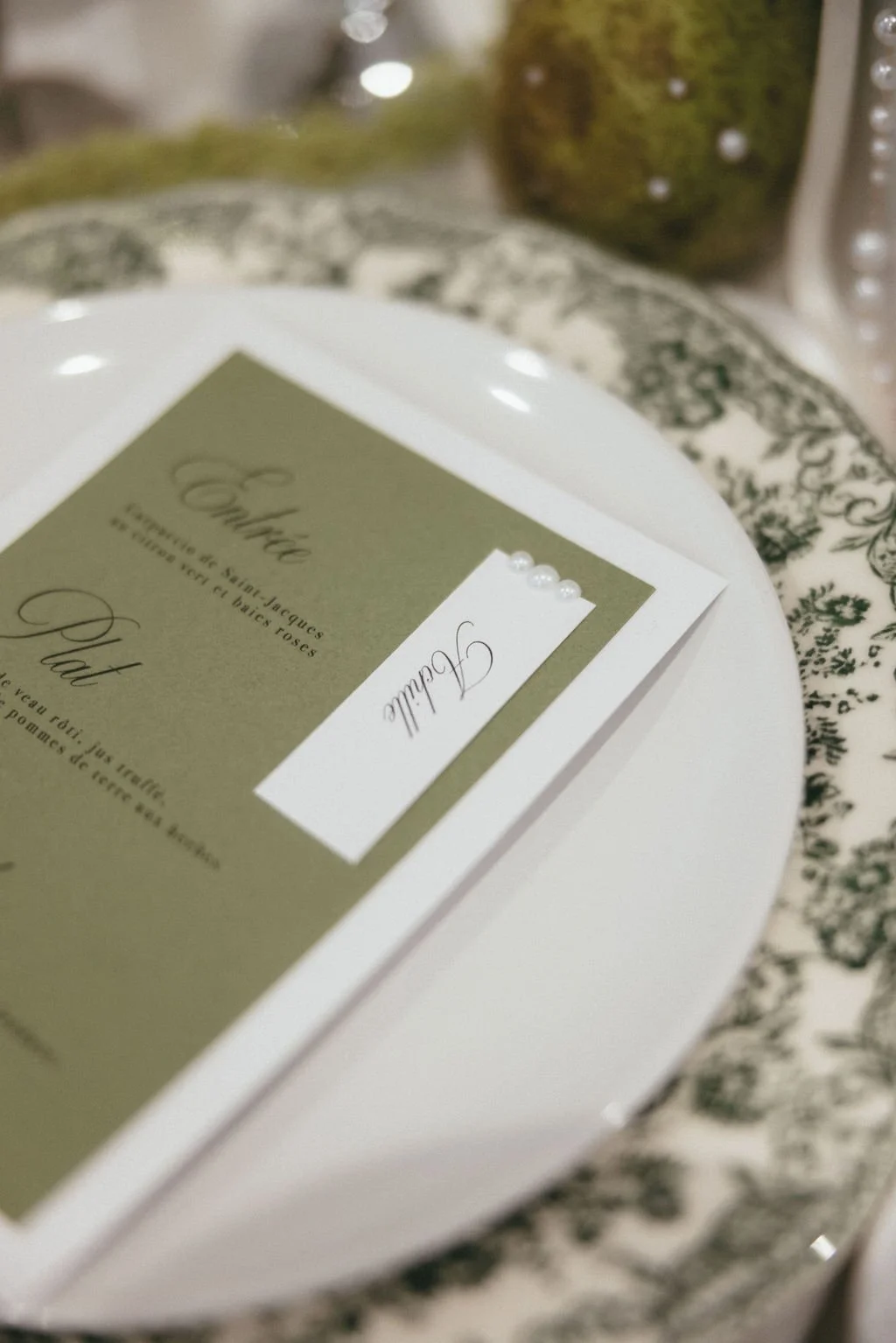 Menu de mariage vert sur assiette ancienne, inspiration papeterie raffinée et intemporelle.