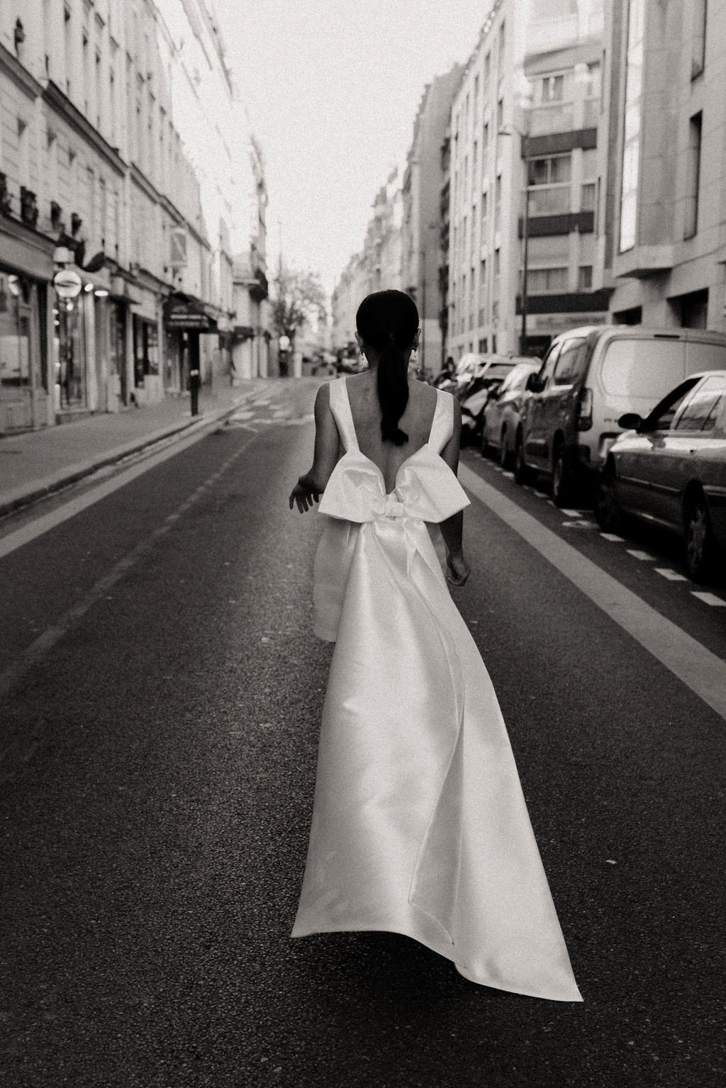 Mariée vue de dos dans une rue urbaine, scène iconique du mariage civil parisien.