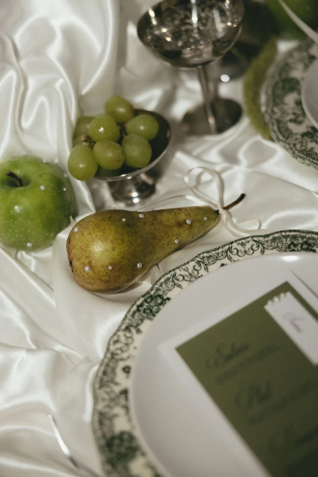 Décoration de table mêlant raisins, poire et argenterie pour un mariage naturel et sophistiqué.
