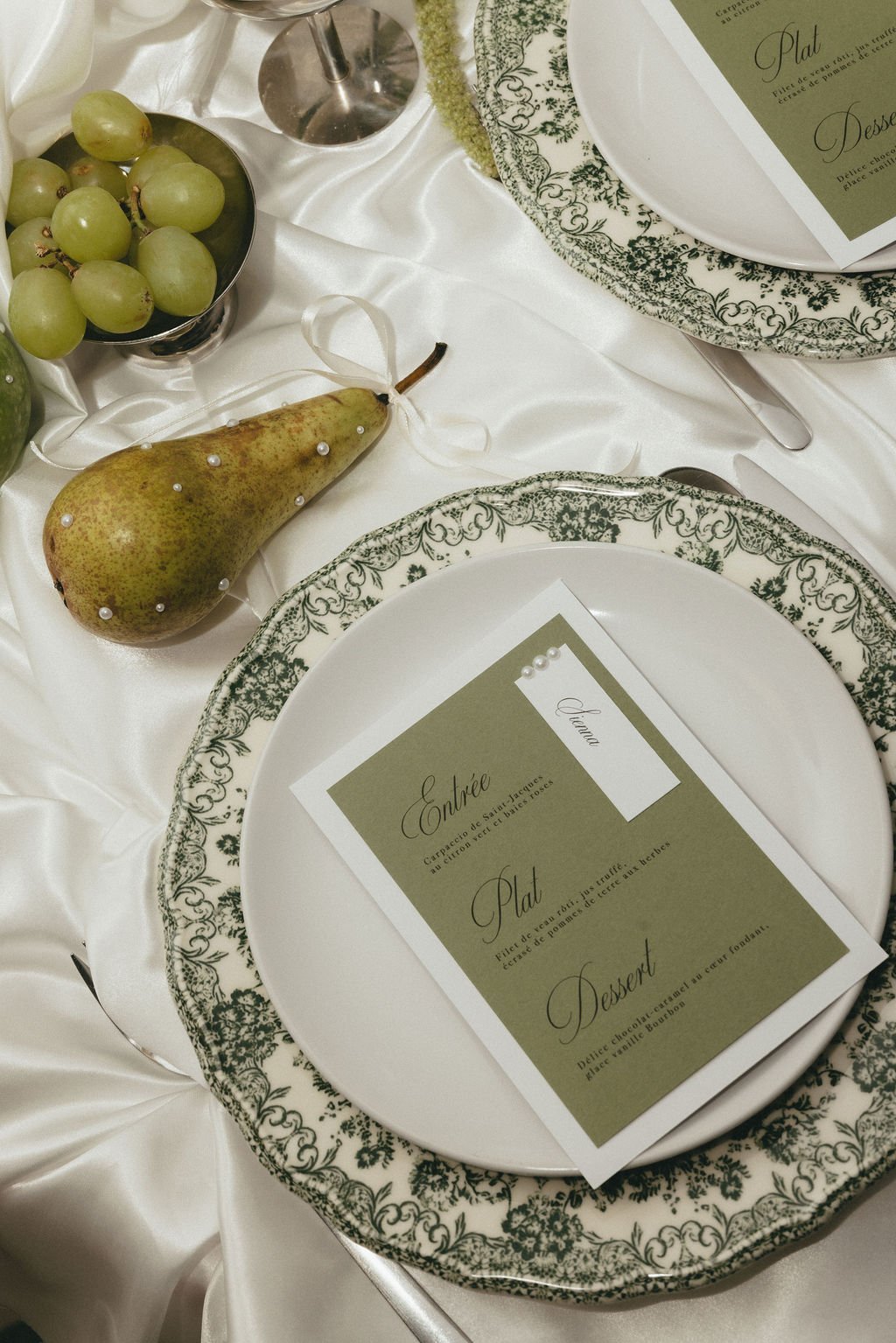 Table de mariage élégante associant vaisselle ancienne et papeterie verte.