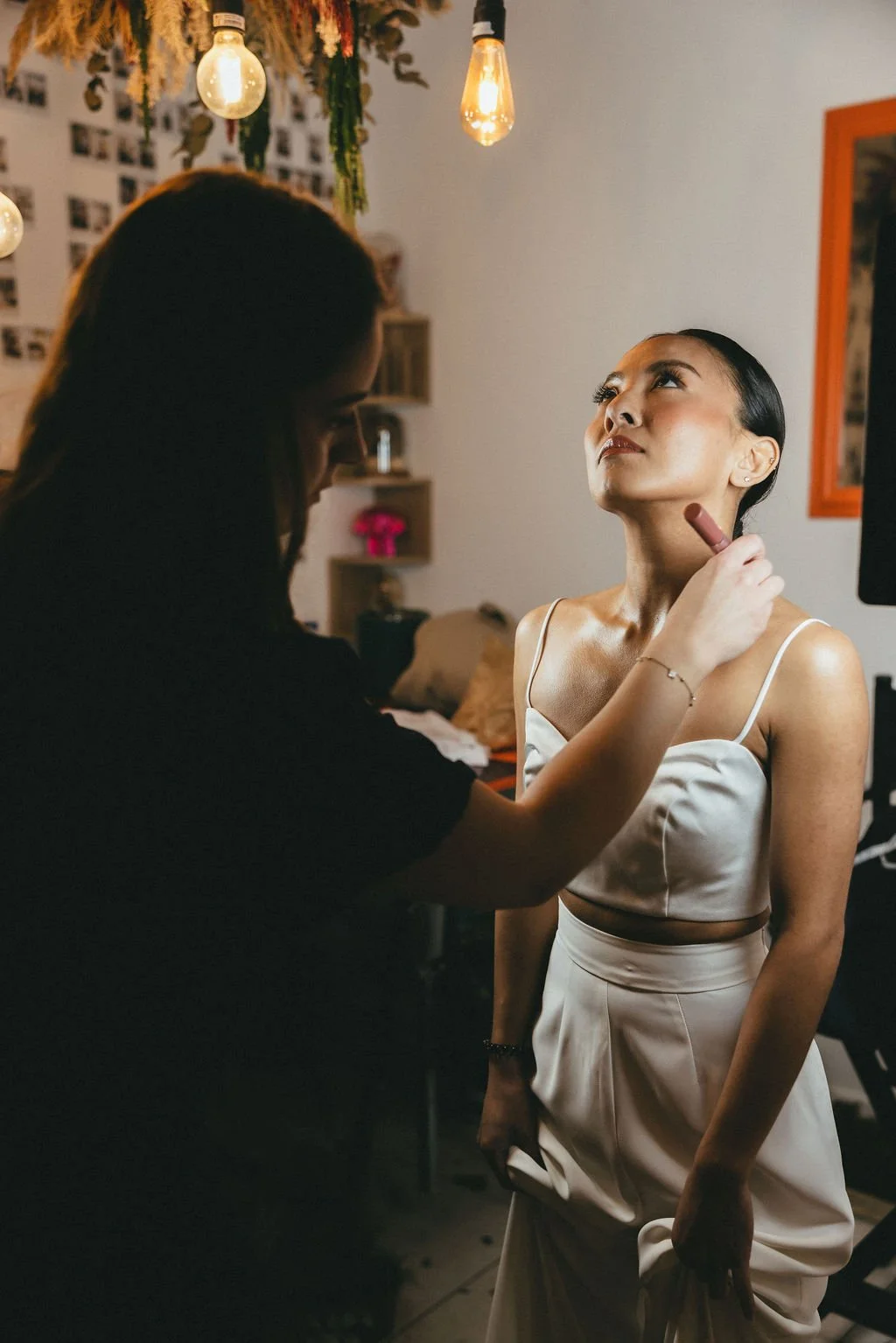 Moment intime de préparation de la mariée, entre maquillage et derniers ajustements avant la cérémonie.
