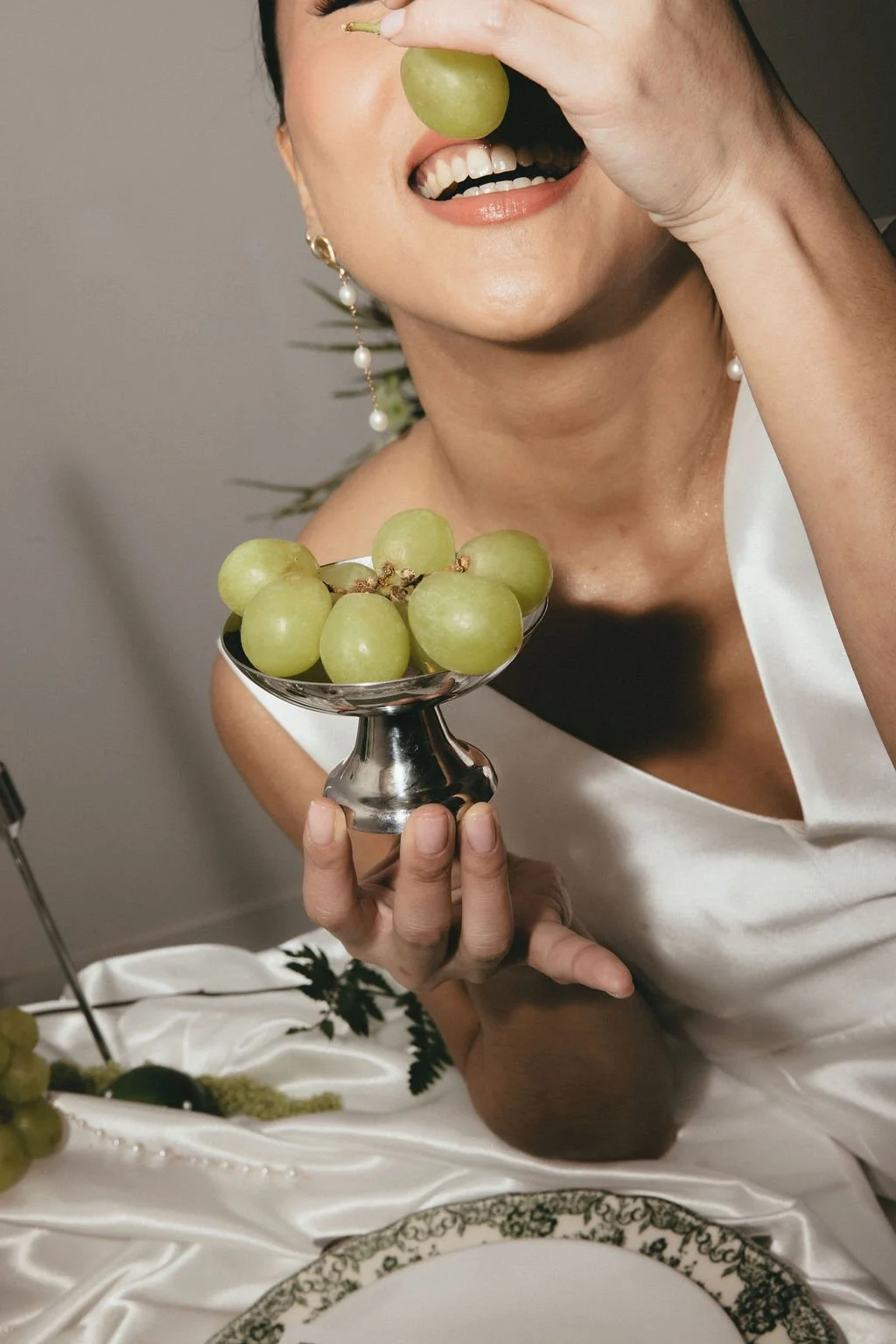 Mariée souriante tenant des raisins verts, clin d’œil ludique et organique.