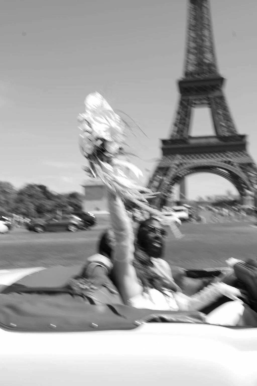 La mariée pose dans une voiture décapotable avec son bouquet devant la tour Eiffel après son mariage civil à Paris.