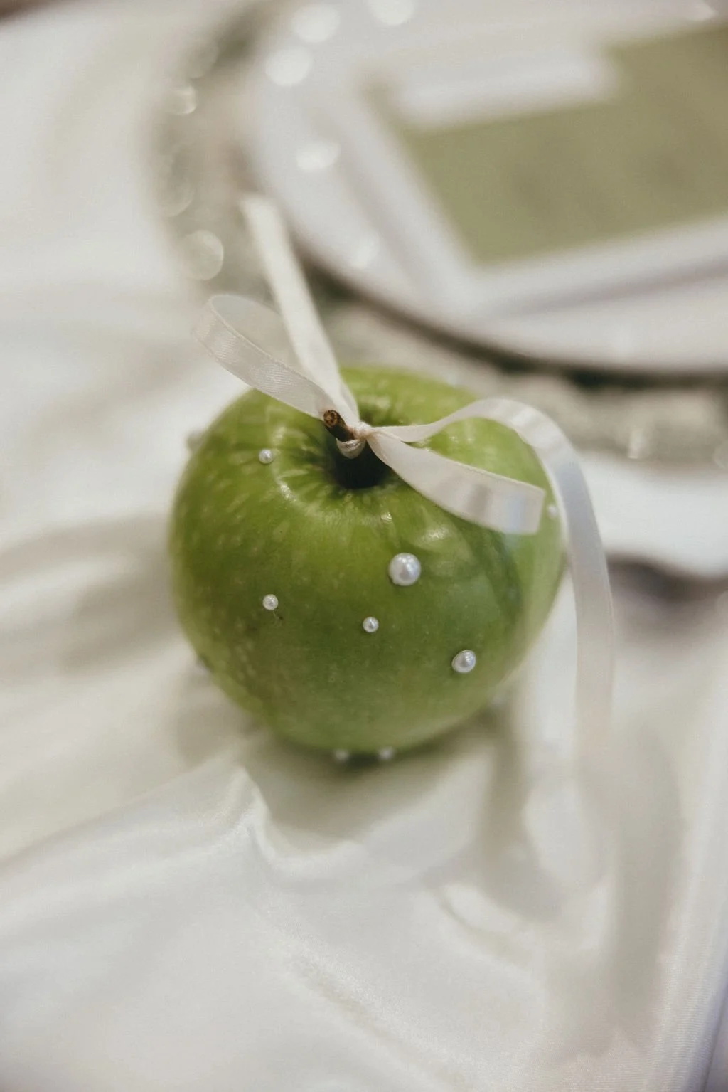 Pomme verte ornée de perles, détail subtil et original pour une table de mariage élégante et créative.