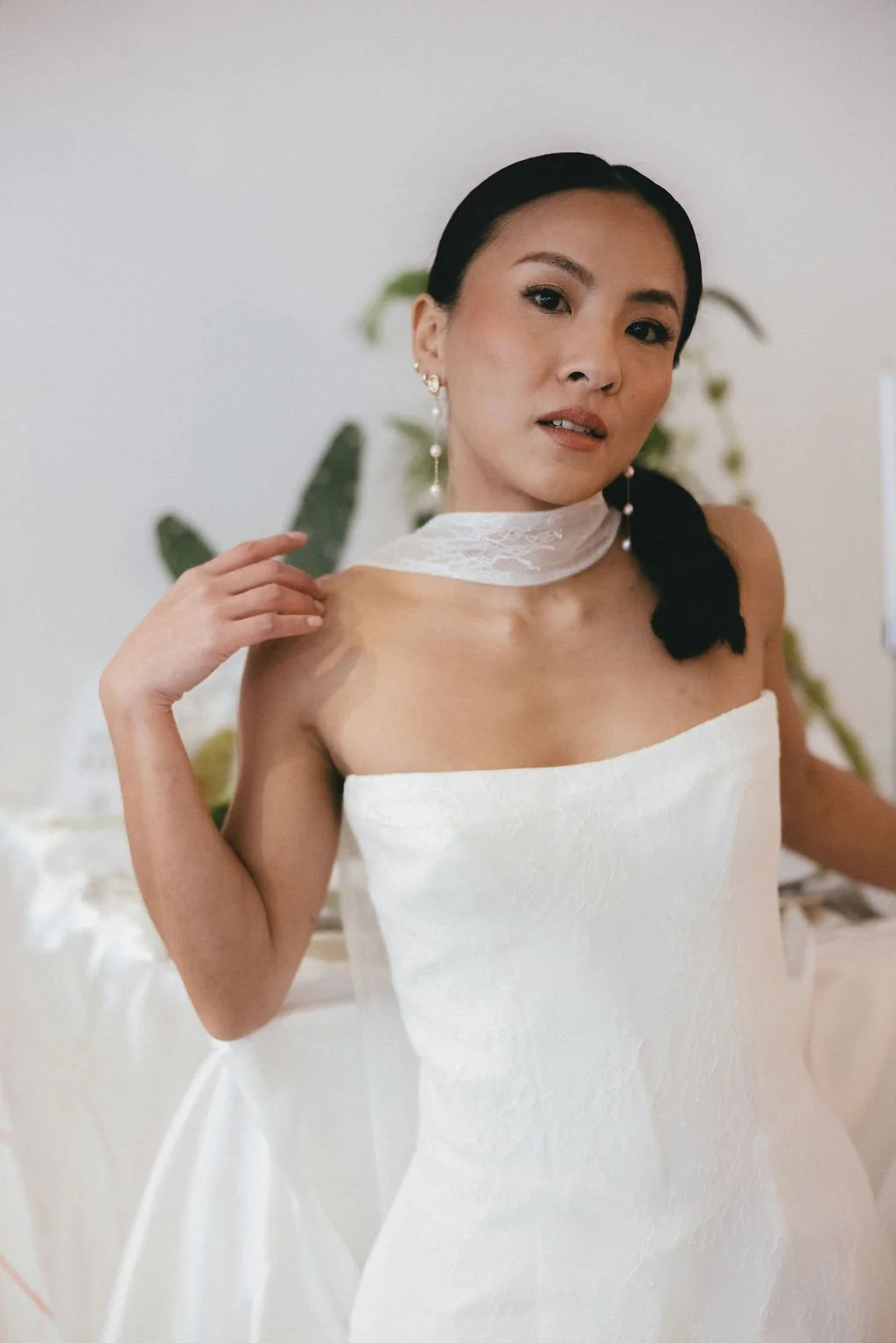 Geste délicat de la mariée ajustant son col, inspiration mode et couture.