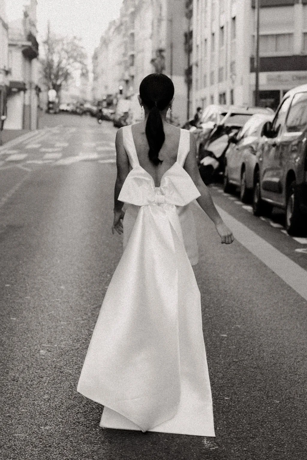 Silhouette de mariée vue de dos, robe fluide et grand nœud pour une allure couture.