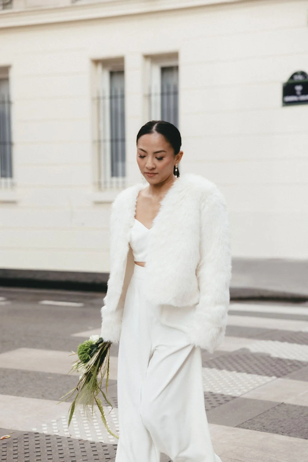 Mariée marchant en ville avec son bouquet, capturant un moment naturel et spontané.