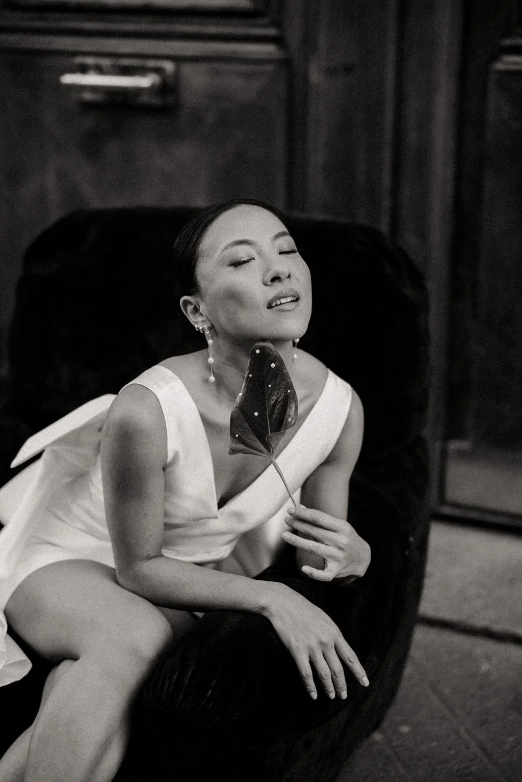 Mariée tenant une feuille verte, détail naturel et graphique pour un mariage contemporain.