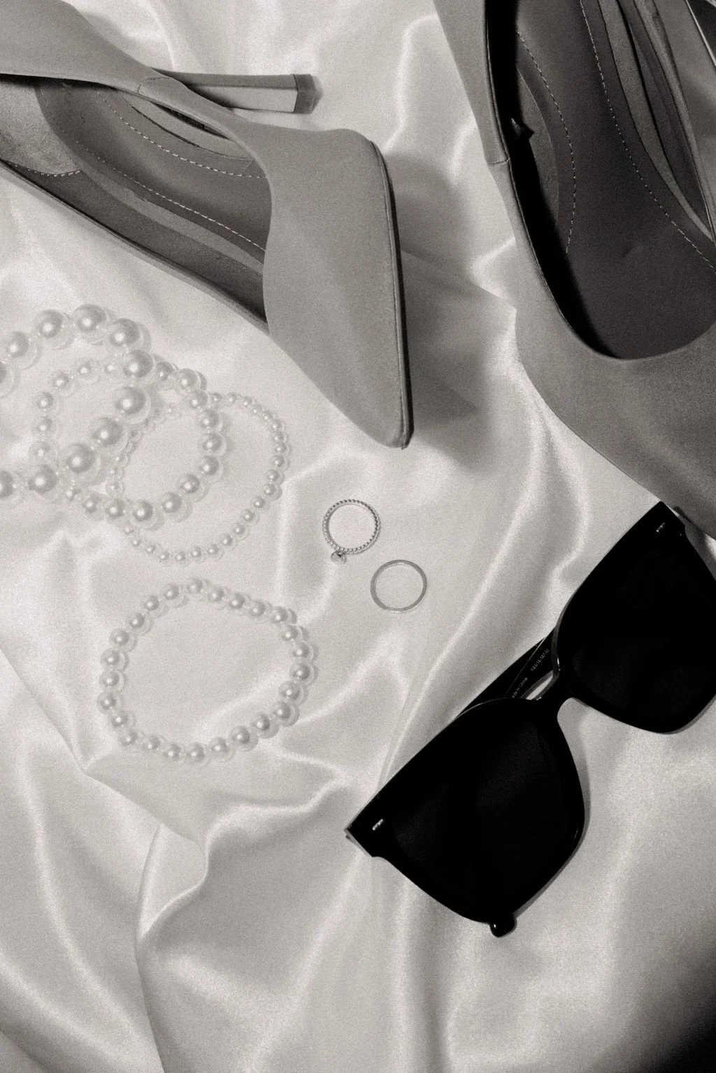 Perles délicates et escarpins sur tissu satiné, inspiration mariage sophistiquée.
