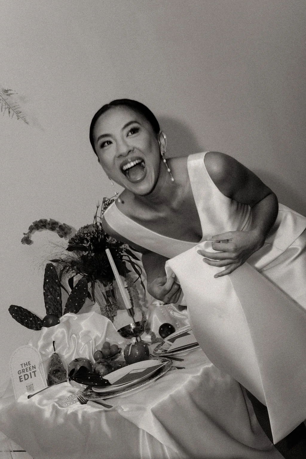 Mariée se penchant vers la table, capturant un instant vivant et spontané.