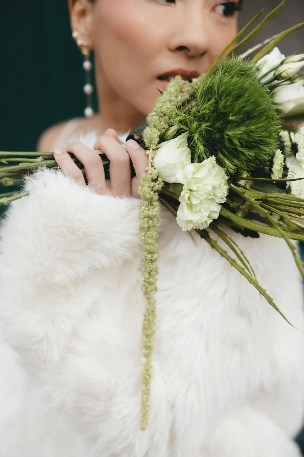 Gros plan sur un bouquet de mariée aux tons verts, signature florale moderne et organique.