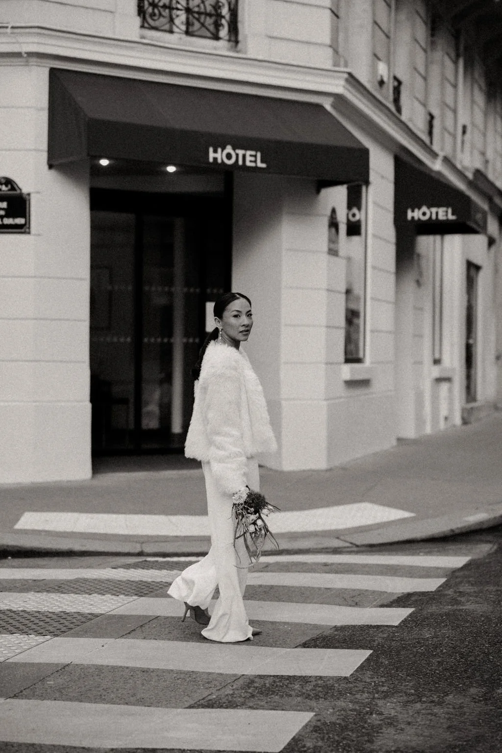 Mariée en tenue blanche traversant un passage piéton, symbole d’un mariage urbain et contemporain.