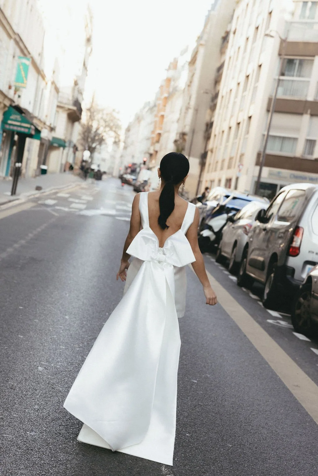 Mariée vue de dos dans une rue urbaine, scène iconique du mariage civil parisien.