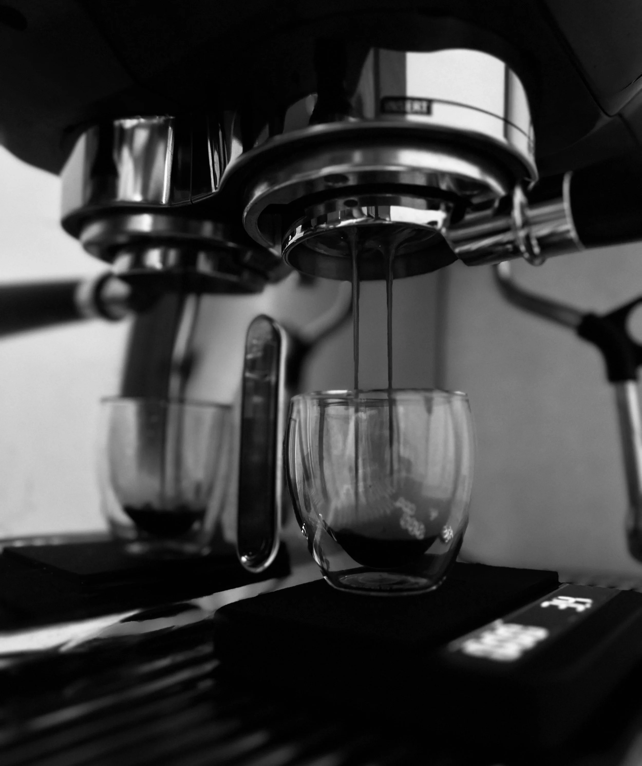 Close-up of an espresso machine pouring coffee into a glass cup.