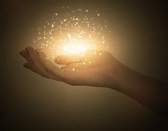 Une main humaine tenant une lumière brillante avec des particules scintillantes autour, symbolisant le magnétisme, l'énergie.