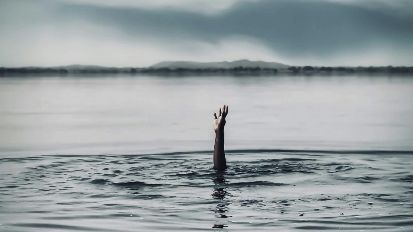 Une main émerge de l'eau dans un environnement sombre et brumeux.
