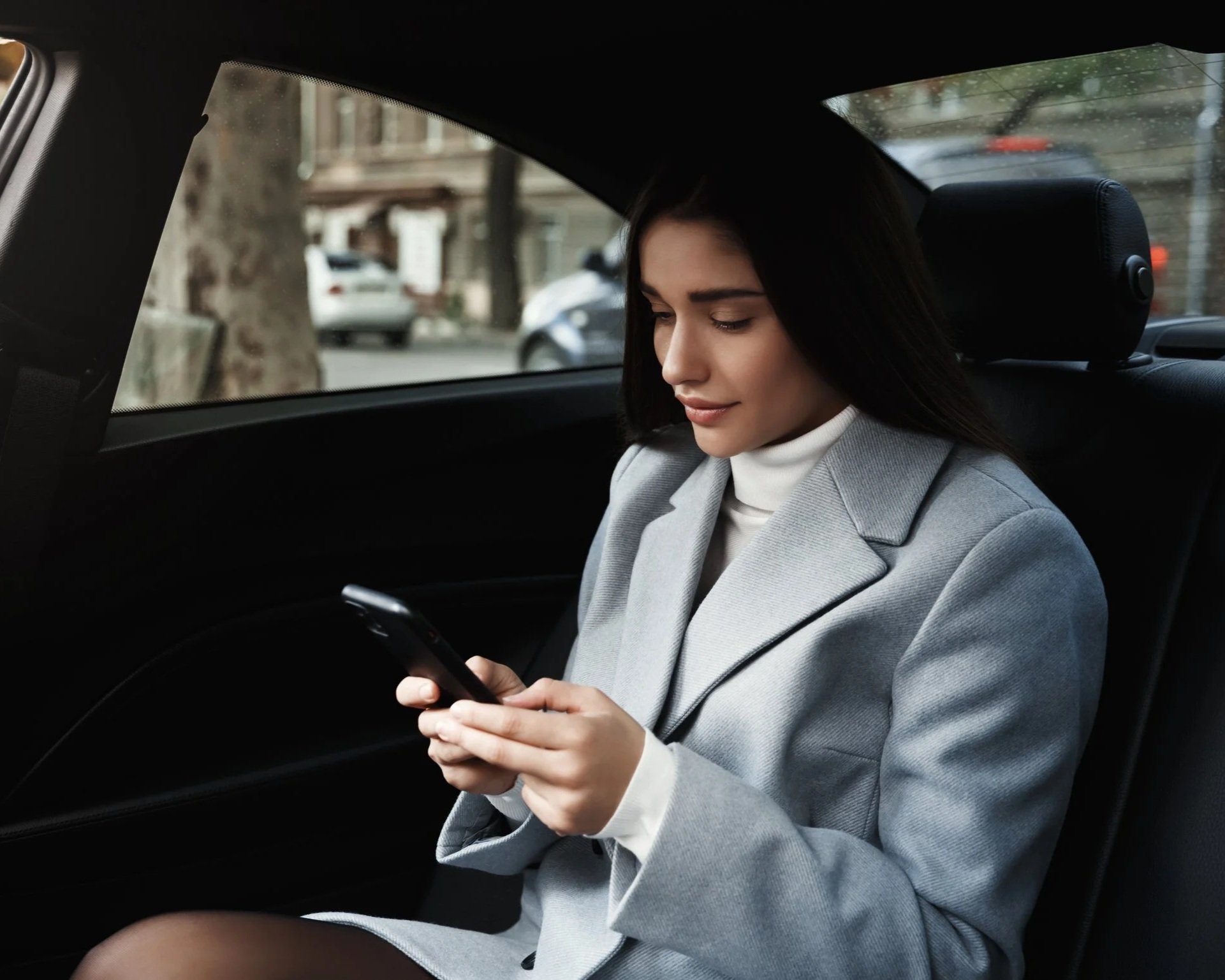 Passagère consultant son smartphone à l'arrière d'un véhicule de transport privé