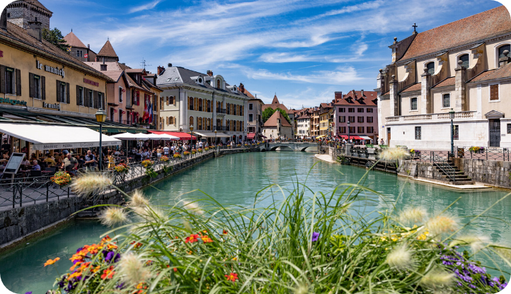 Vue sur les canaux et les façades colorées du vieil Annecy en été, avec terrasses animées