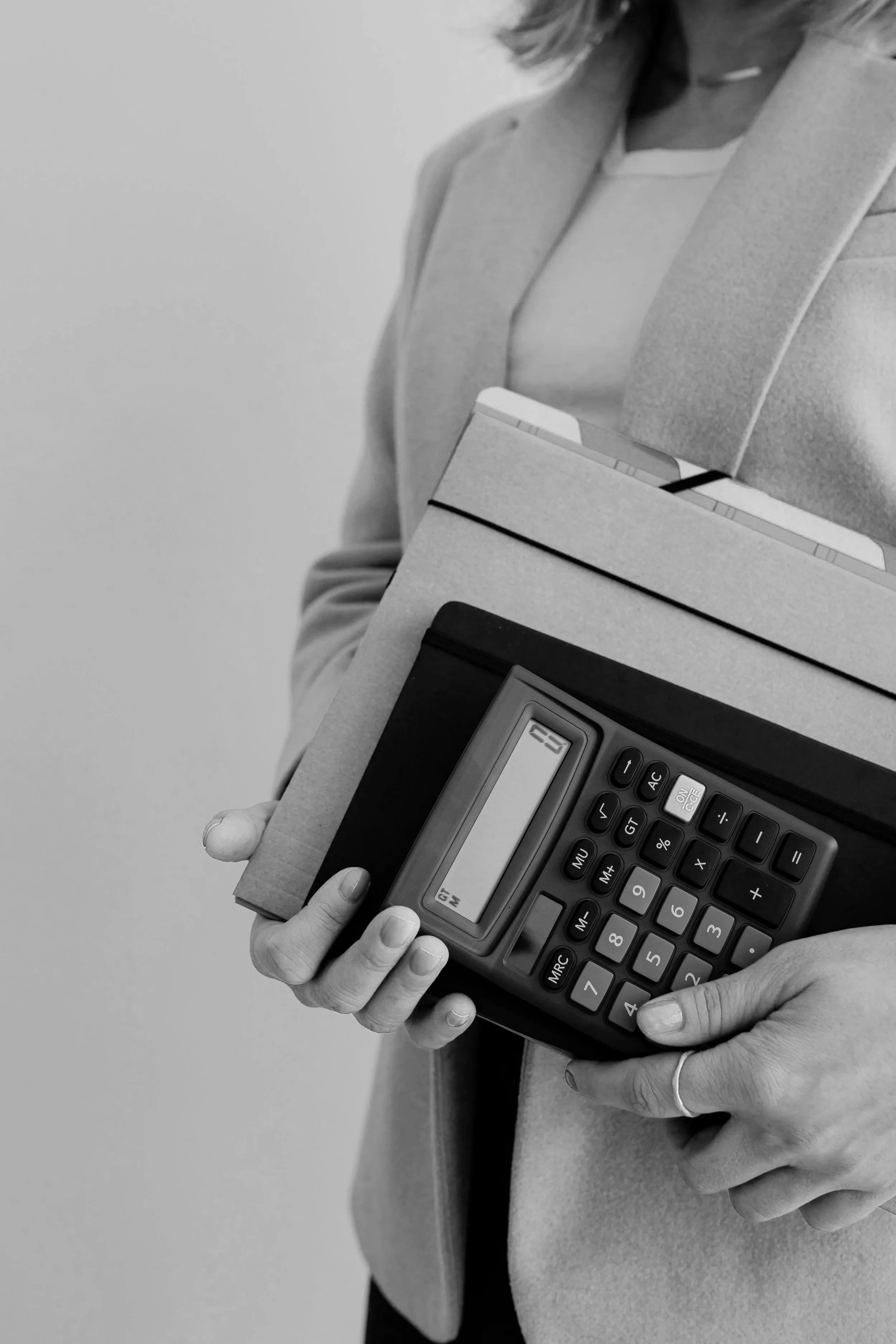 Eine Frau hält einen Ordner, eine Tastatur und ein Tablet in den Händen.