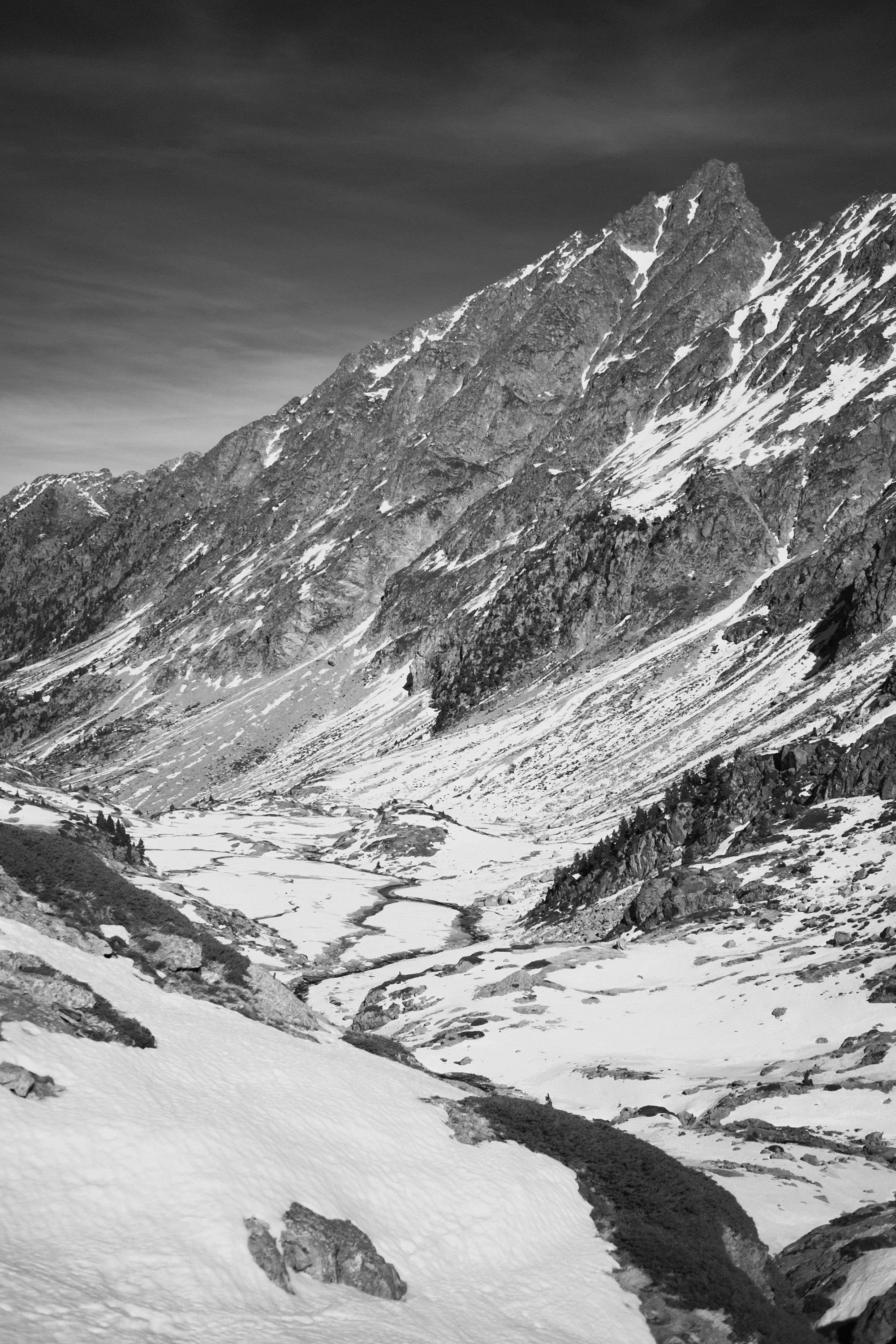 Snow-covered mountainous landscape with a river valley and cloudy sky. Urth, infrared filter
