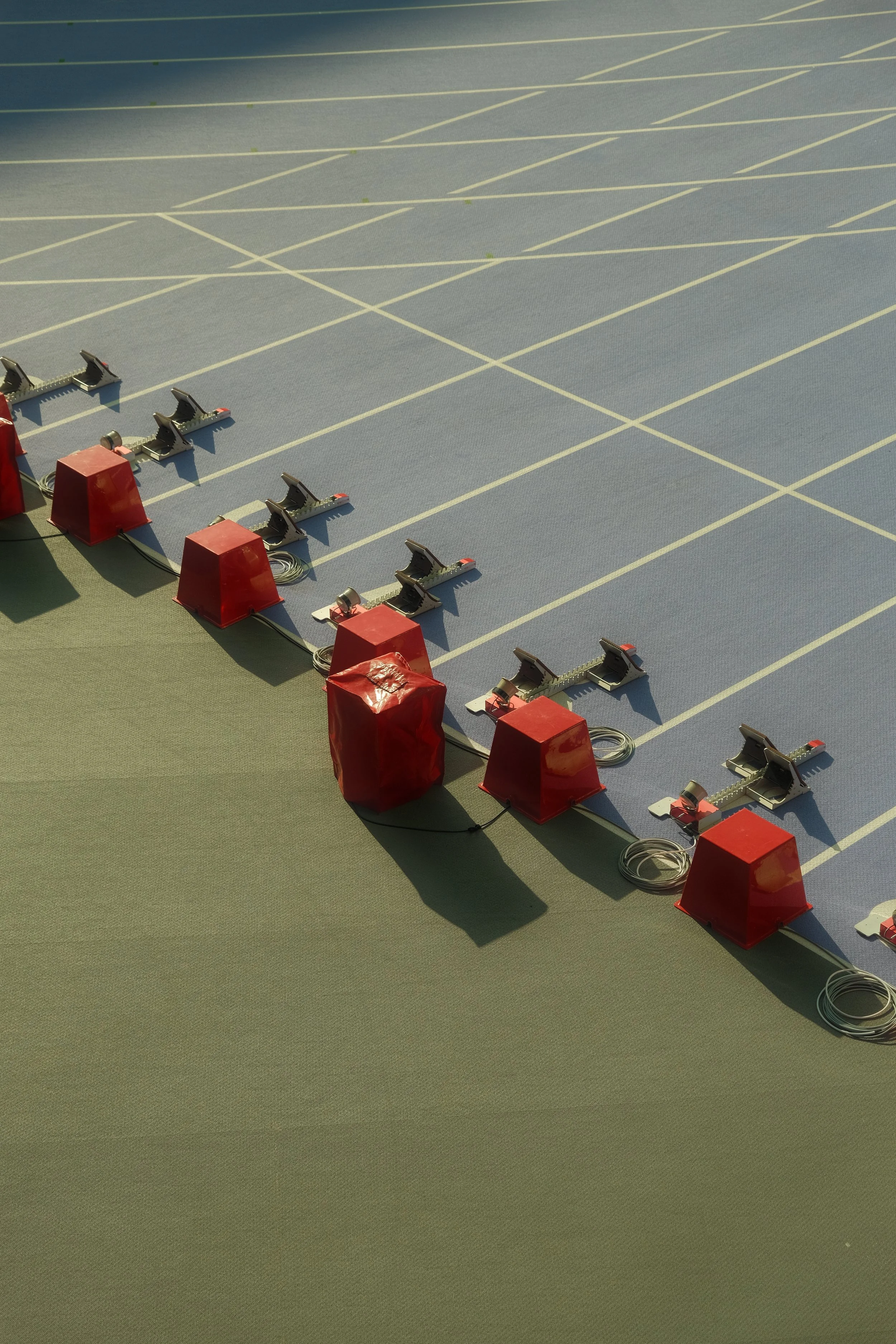 Olympic or athletic track starting blocks with red cones on green and blue lanes. Olympic Games, Paris 2024