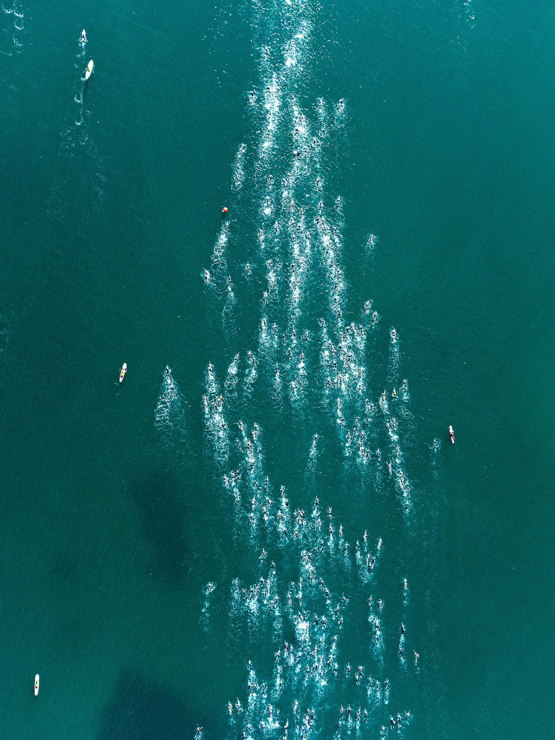 Aerial view of multiple paddleboarders and boats on a large body of water during the traversée de Saint Jean de Luz
