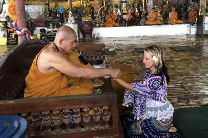 American lady tourist receiving monk blessing in Phuket, Thailand