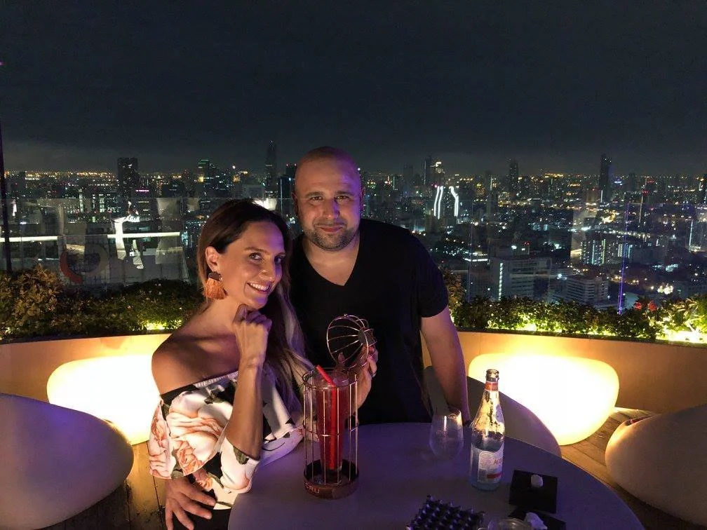 Married couple enjoying craft cocktails at Red sky Bar in Bangkok where the drinks come served in bird cages.