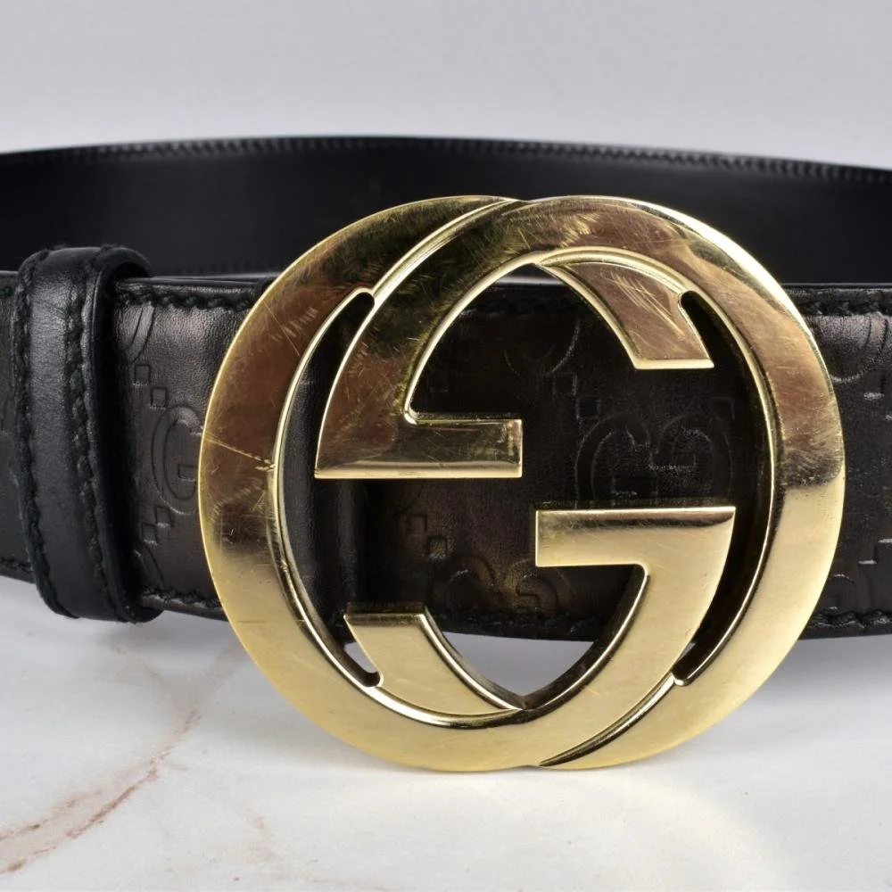 Close-up of a Gucci belt with a large gold double G logo buckle on a black leather strap.