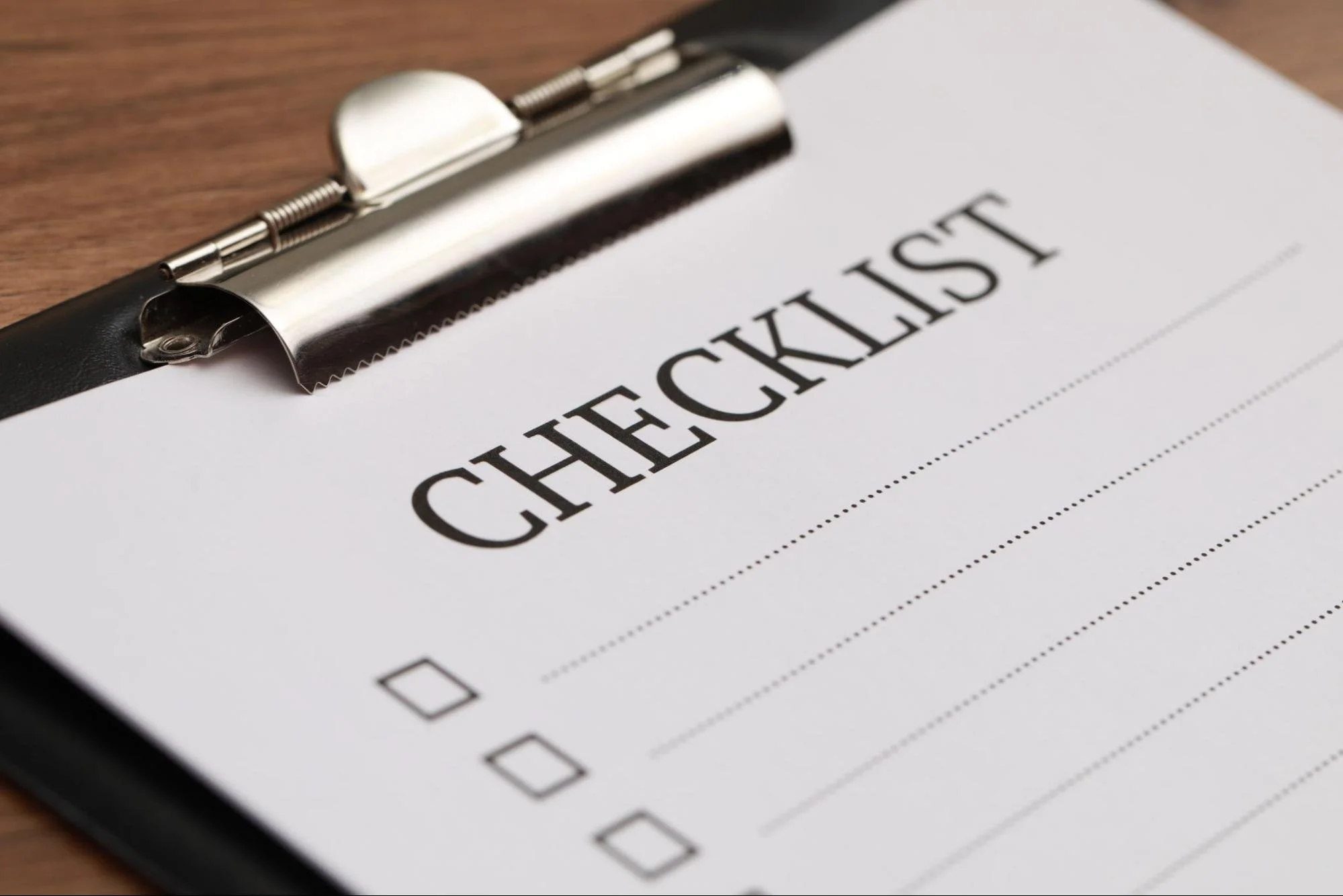 Word “checklist” on a piece of paper on a clipboard.