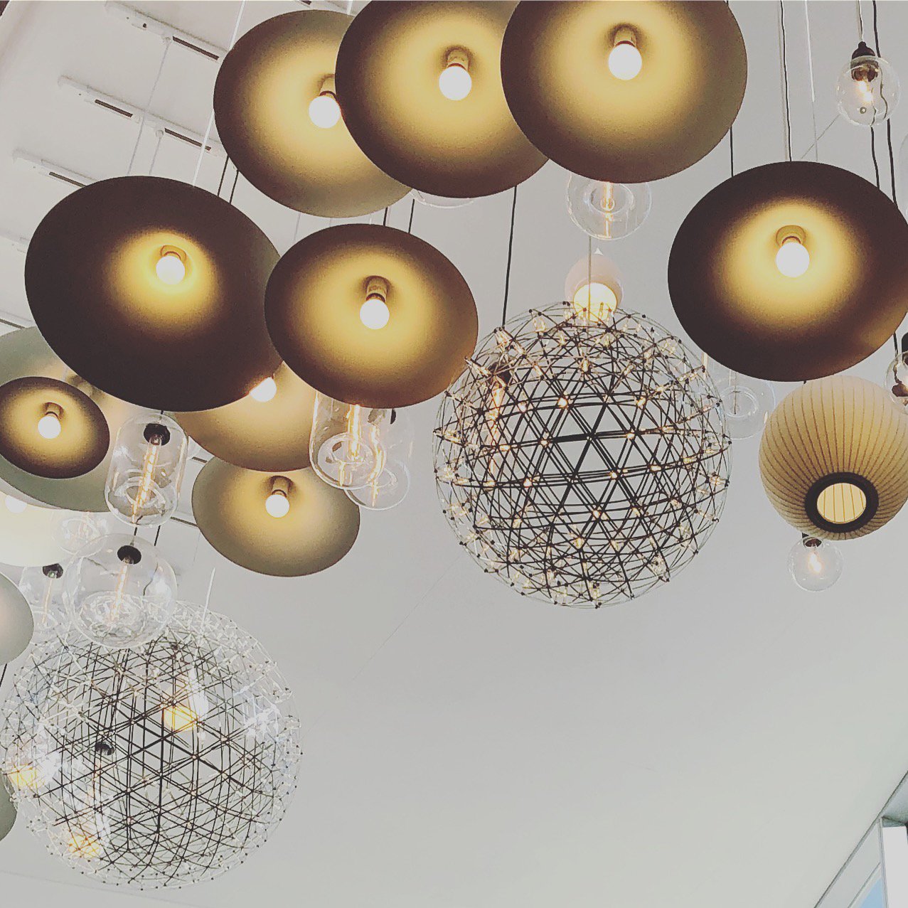 Ceiling lights with various styles, including some with black shades and others with wireframe spherical designs, hanging from the ceiling.
