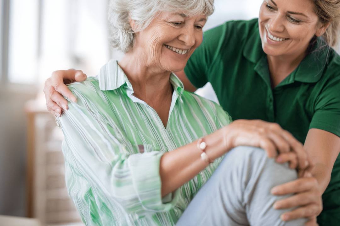 A professional mobile physiotherapist provides compassionate knee rehabilitation and mobility support to an elderly female patient in a home care setting in Perth.