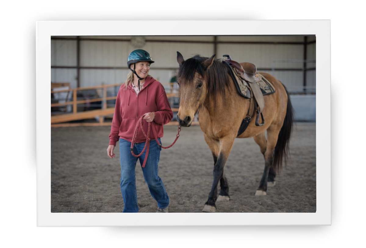 A calm moment in the arena at HorseSpeak, with a staff member leading a horse gently as part of therapeutic riding support.