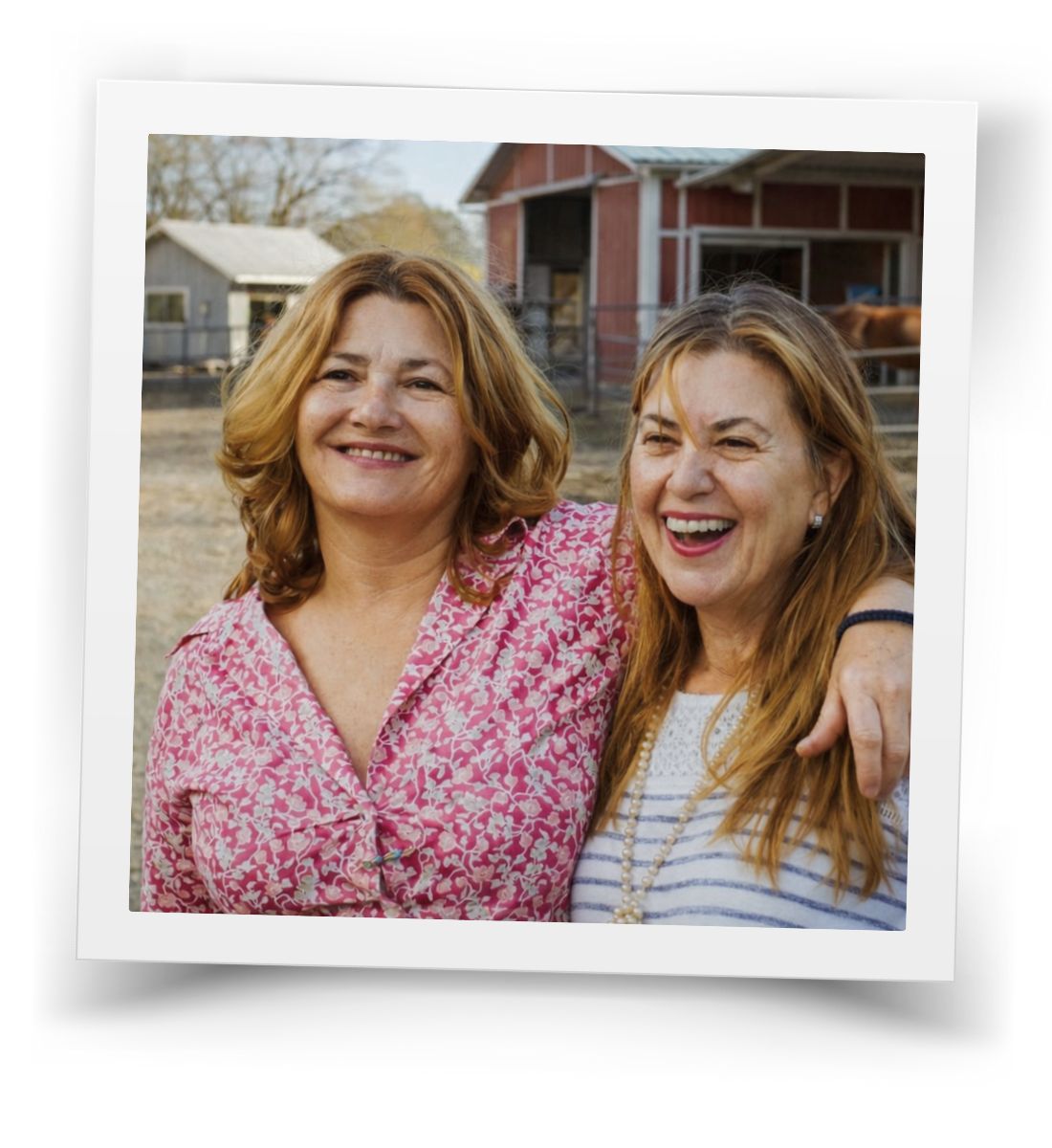 Two HorseSpeak volunteers smiling together outside the barn at the ranch.