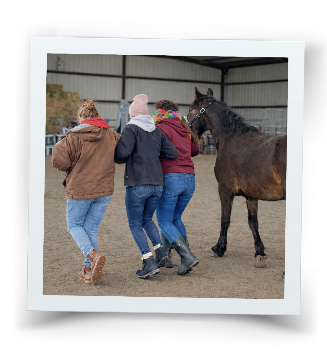 Three women walking arm in arm beside a horse during a therapy session at HorseSpeak