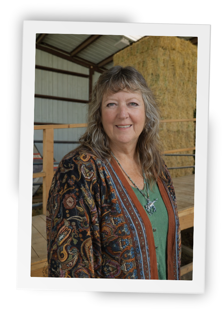 Leslie, equine-assisted therapist at HorseSpeak, standing inside the ranch barn